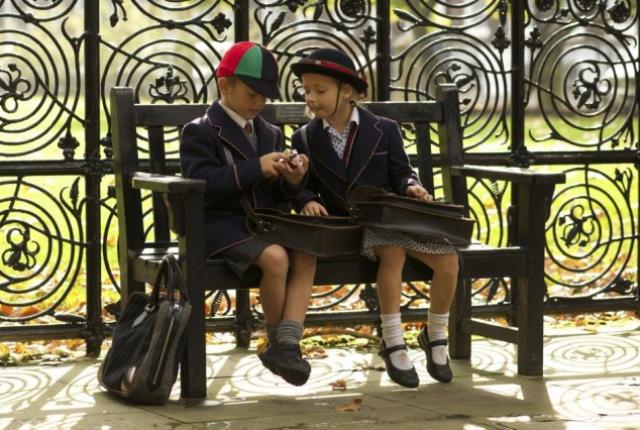 Two children sitting on an outdoor bench at their UK school, representing the work of William Clarence’s global and overseas education consultants.